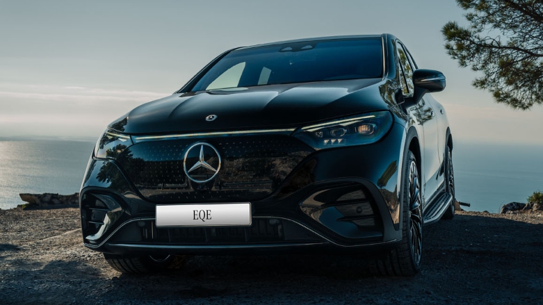 Mercedes Benz EQE SUV color negro estacionado estacionado en terreno rocoso con el mar de fondo.