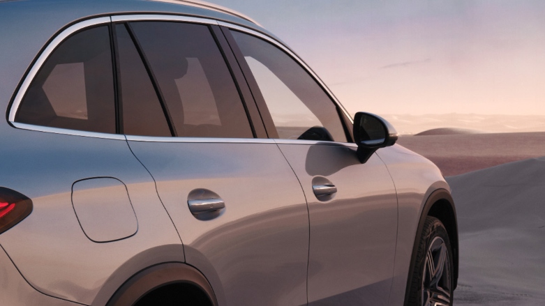 Vista lateral trasera de Mercedes Benz GLC color gris sobre terreno arenoso.